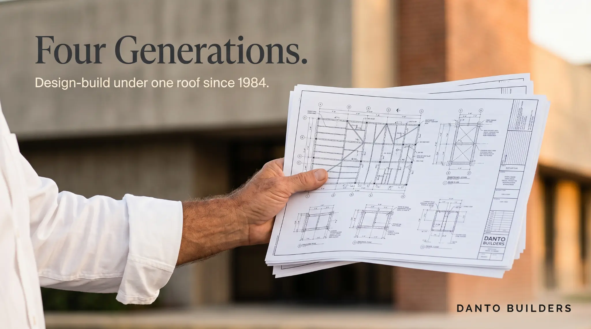 Four Generations brand hero — man holding blueprint sheets